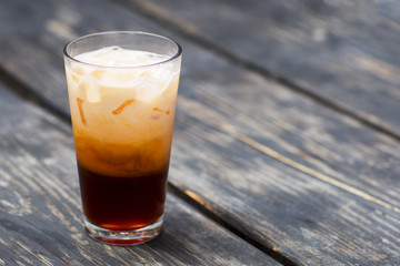 Iced tea with ice cream in a glass cup. Cold drink with ice on a wooden table. 