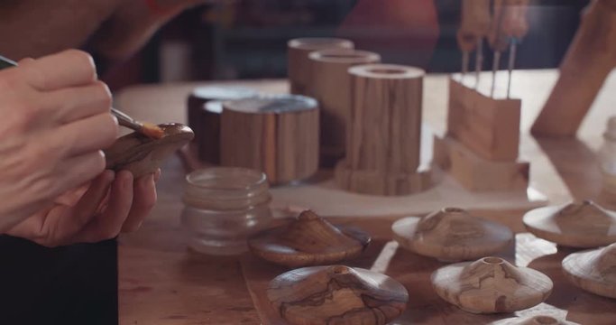 Artist using brush to apply lacquer to a wood Buddhist prayer wheel