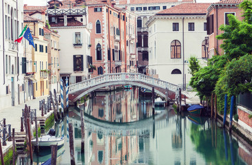 Fototapeta na wymiar Bridge over canal in Venice, Italy. Traditional architecture also reflected in the water