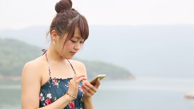 リゾート地でスマートフォンを使う女性