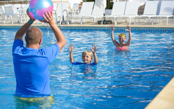 Family Playing With Colorful Beach Ball In  Swimming Pool