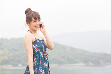 海でスマートフォンを使う女性