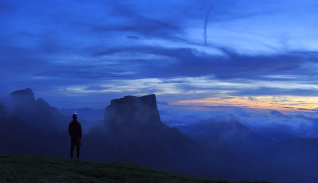 Hiker at his tent looking at a new dawn in the mountains.