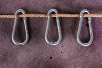 Three carabiner weigh on a rope. Background splattered paint.
