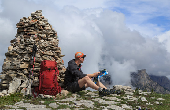 Hiker at a cairn, checking his map for navigation.