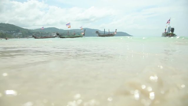 Tropical beach with fishing boats and yellow sand. Beautiful clouds and waves of the sea.