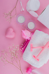Set for SPA: cotton swabs, razors, cotton pads, towels, napkins, bath salts on a pink background flat lay.