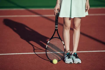 Foto op Canvas Legs of sportive girl near the tennis racquet and balls on tenni © tatyanasuyarova