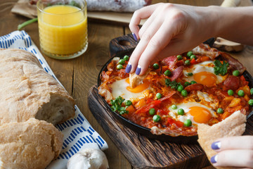 Hand of the girl dip bread into eggs a la flamenca