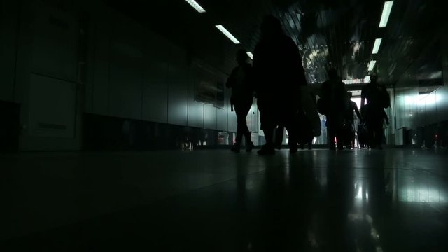 Silhouettes of people at the airport. Arriving passengers walk along the corridor.