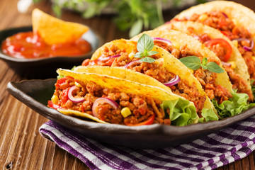 Tacos with meat and vegetables on wooden board