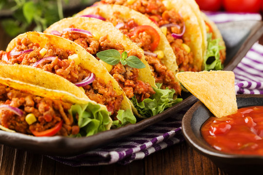 Tacos with meat and vegetables on wooden board
