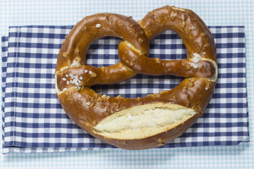 Bayrische Brezel auf weiß-blau karierter Serviette im Querformat