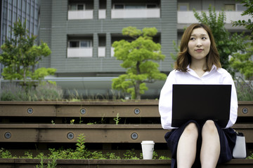 Japanese businesswoman using laptop computer on steps outside in Tokyo