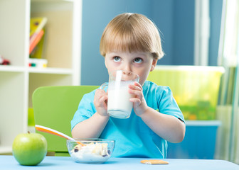 Portrait of happy young boy holding glass with milk