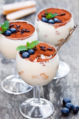 Tiramisu  dessert in a clear glasses on a rustic wooden backgrou