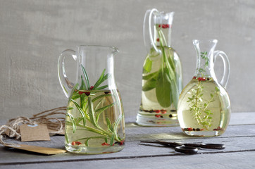 verschiedene Kräuteröle mit Thymian, Salbei und Rosmarin in Glaskaraffen