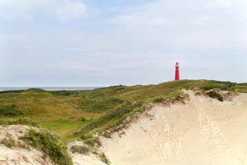 Fototapeta na wymiar Red lighthouse in the dunes of the dutch island Schiermonnikoog