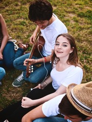 group of friends together in a park having fun and playing music with a guitar