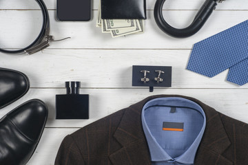 set of men's clothing and shoes on wooden background. Men accessories. Black elegant accessories pieces isolated on white wooden table. Top view. Copy space for text.