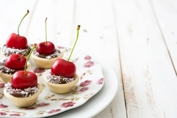 Delicious chocolate tartlets with chocolate, cherries and coconut

