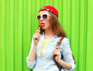 Fototapeta premium Portrait pretty cool girl with lollipop over green background