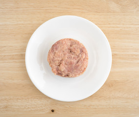Canned smoked ground ham on a plate atop a wood table top.