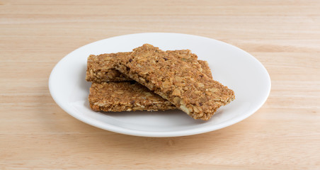 Cinnamon sesame and pumpkin seed granola bars on a plate atop a wood table top.