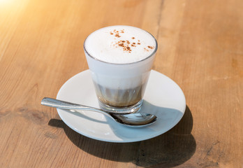 Hot cappuccino on the table with coffee shop background
