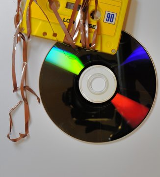 Vintage yellow musicassette with damaged tape and CD ROM. Selective focus.
