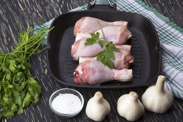 raw chicken drumstick in pan with salt, garlic, parsley
