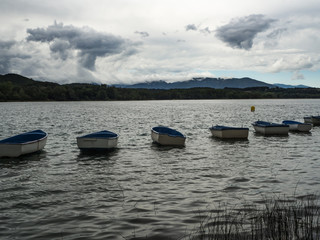 Vista del paisaje del lago de Banyoles de Girona con barcas en fila flotando sobre el agua y nubes...