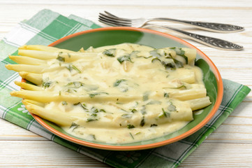 White asparagus with delicious cheese sauce on wooden background.