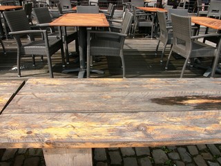 Holztische mit Rattanstuhl in Dunkelgrau am Kreativkai bei Sonnenschein an der Hafenpromenade im...