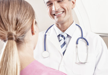 Happy young male doctor speaking with female patient undergoing