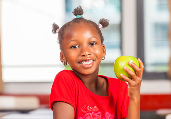 African girl at school holding green apple fruit