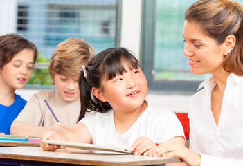 Happy elementary multi ethnic students with teacher