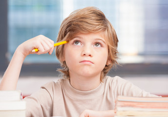 Elementary school boy at classroom desk trying to find new ideas