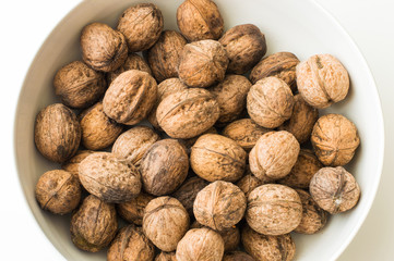 Walnuts in shell in a white bowl