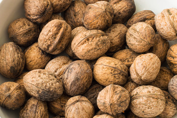 Walnuts in shell in a white bowl