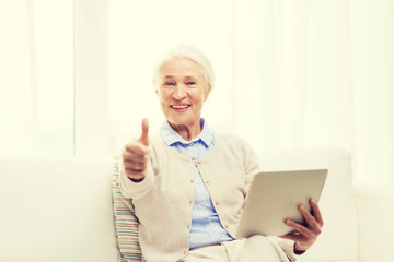senior woman with tablet pc showing thumbs up 