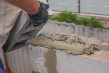 builder puts a cinder block for the construction of the building. skillful hands puts a brickwall. cinder blocks.