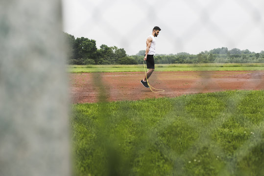 Athlete skipping rope on sports field