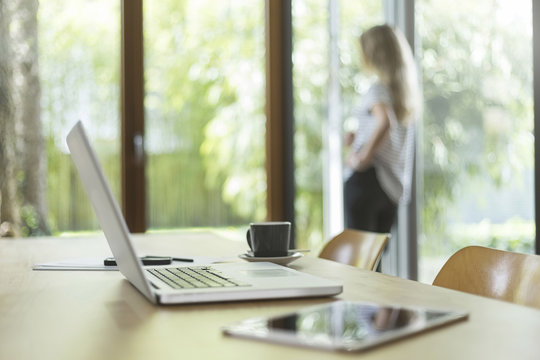 Laptop and digital tablet on table with woman in background