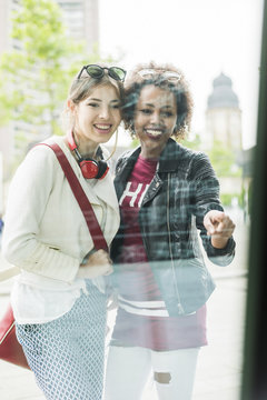 Two young women looking in shop window