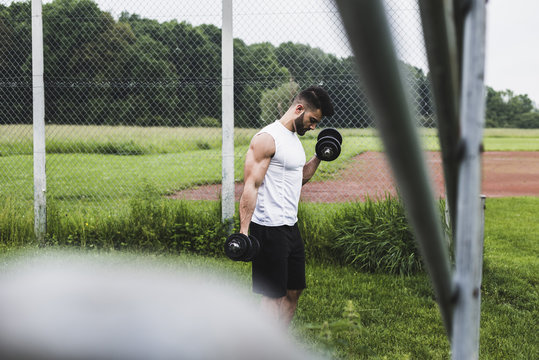 Athlete exercising with dumbbells on sports field