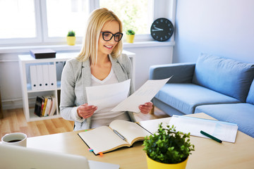 Young woman comparing documents while working from home office