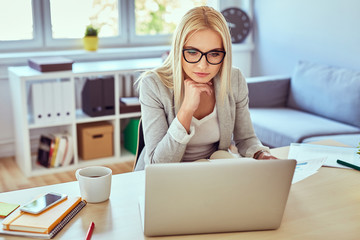 Thoughtful woman working on laptop from home