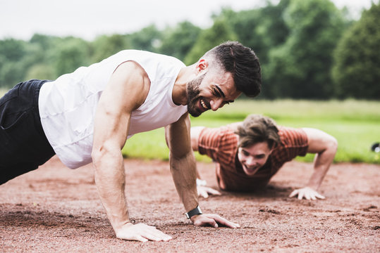 Two athletes doing pushups on sports field