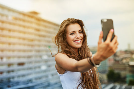 Happy young woman taking selfie on rootfop